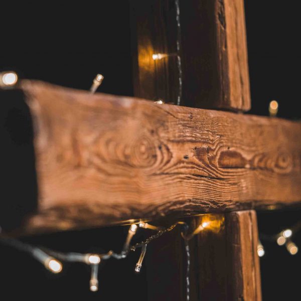 Mit Lichterkette geschmücktes Kreuz aus Holz.